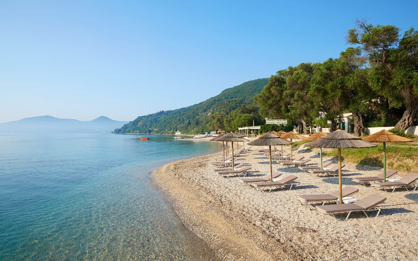 beach with parasol and loungers next to the sea